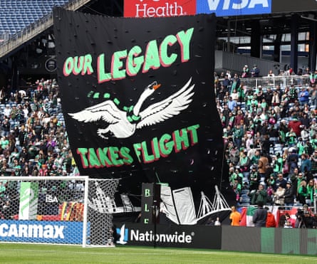 Uma imagem de um tifo com as palavras “Nossa Herança Decola” e um cisne usando uma faixa de futebol.