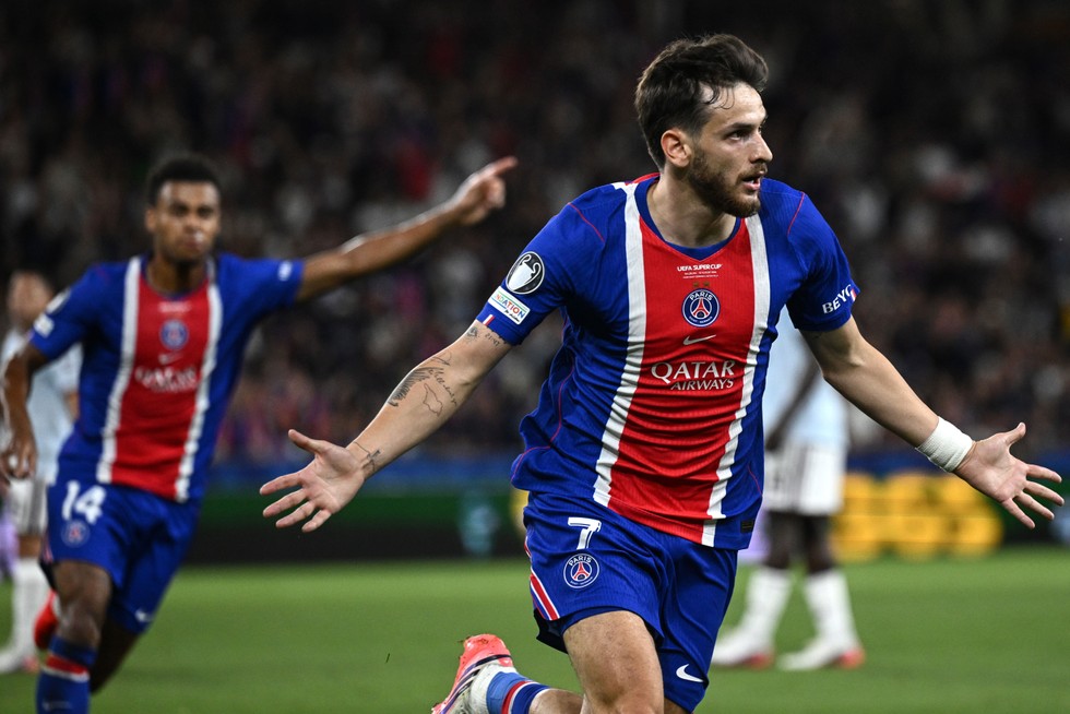 PSG winger Khvicha Kvaratskhelia, in red and blue football kit, celebrates in the Super Cup final.